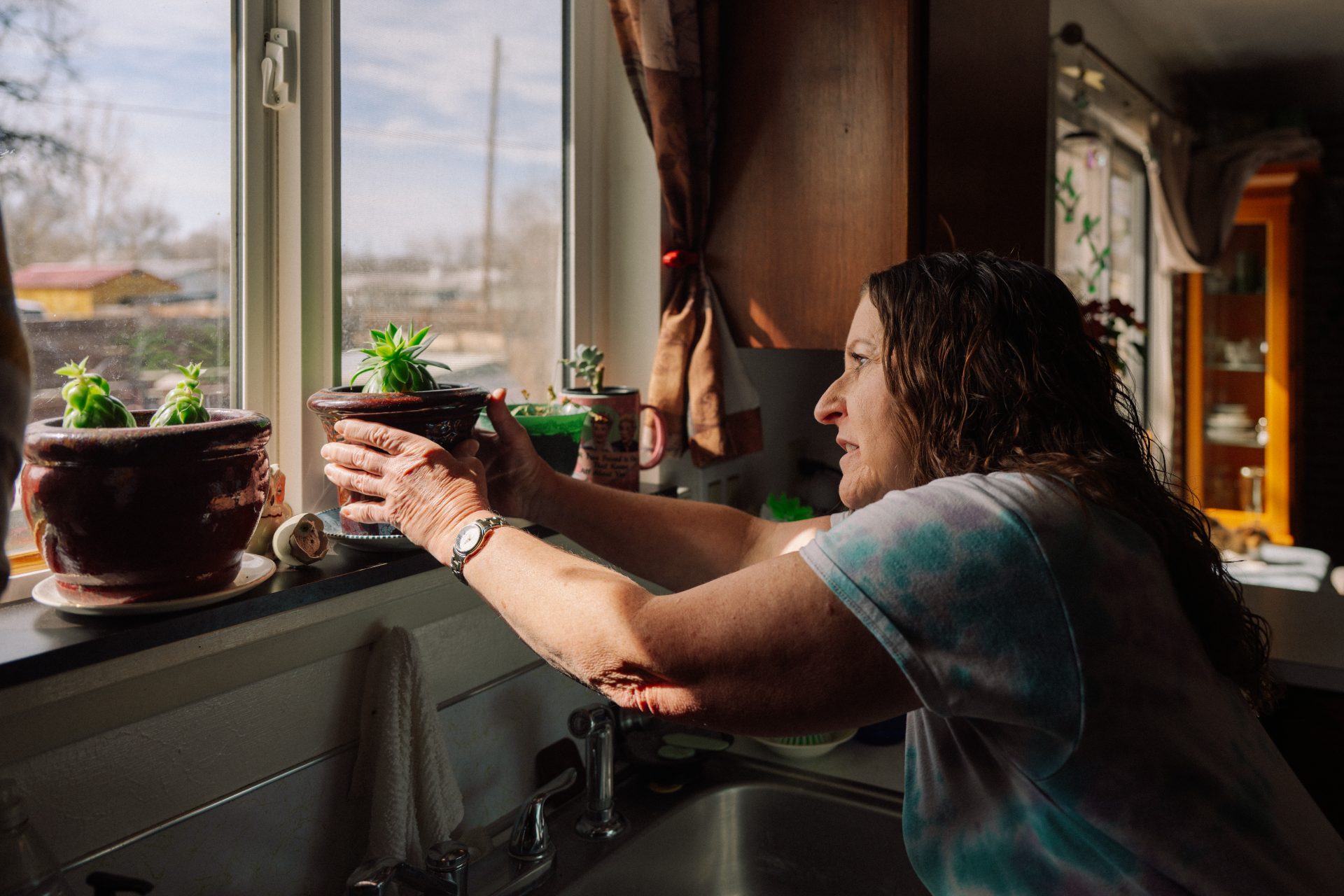 Anita tending plants at her kitchen window, still from Rethink Hunger